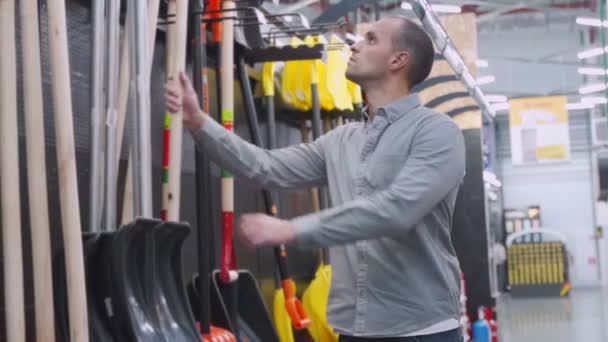 L'uomo sceglie in negozio una pala per la rimozione della neve . — Video Stock