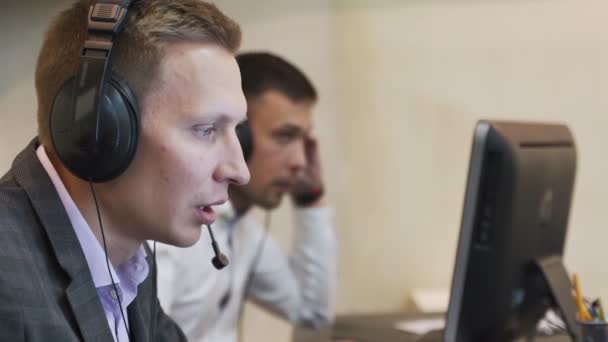 Männliche Callcenter-Agent in drahtlosen Headset Beratung Online-Client. Benutzung des Computers, Geschäftsleute sprechen im Kundendienst-Helpline-Support — Stockvideo