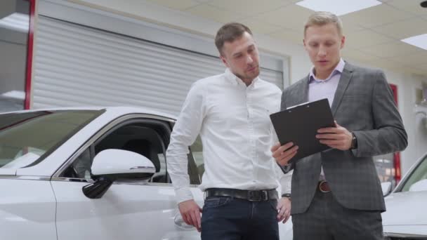 Concesionario de coches explicar el contrato de venta al hombre que compra un coche — Vídeos de Stock