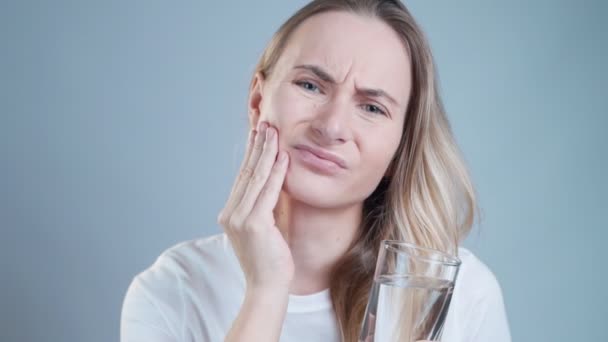 Junge Frau berührt ihre Wange, hat starke Zahnschmerzen und leidet unter Schmerzen — Stockvideo