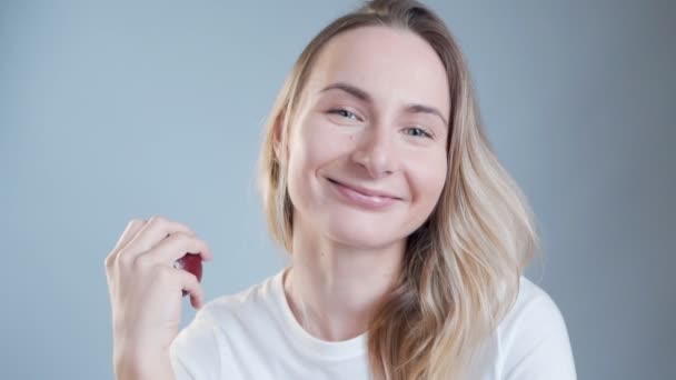 Beautiful happy woman holding an apple over grey background — Stock Video