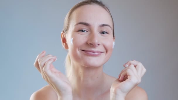 Frau cremt sich ihr Gesicht ein. das Streben nach Schönheit — Stockvideo