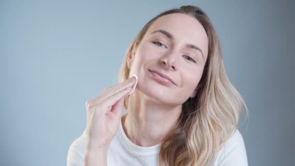 Bella donna che si pulisce il viso con batuffoli di cotone. Cura della pelle e concetto di bellezza . — Video Stock