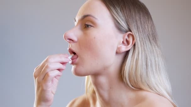 Jonge vrouw neemt pil en drinkt een glas schoon water. meisje houdt medicijnen en glas water vast. — Stockvideo