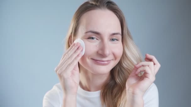Mulher bonita limpando seu rosto com almofadas de algodão. Cuidados com a pele e conceito de beleza . — Vídeo de Stock