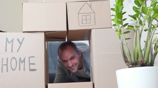Man ontspannen en lachen na het uitpakken van dozen uit huis te verplaatsen. Verhuizen naar een nieuw appartementenconcept — Stockvideo
