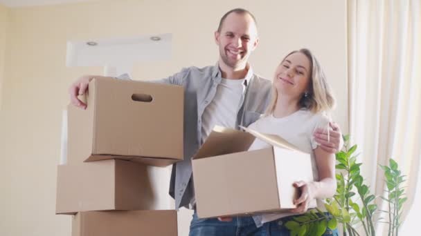 Feliz pareja joven con cajas de cartón en su nueva casa — Vídeo de stock