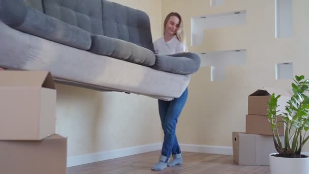 Casal jovem feliz move novo sofá para sala de estar, cair nele para descansar. Apartamento moderno brilhante com mobiliário elegante . — Vídeo de Stock