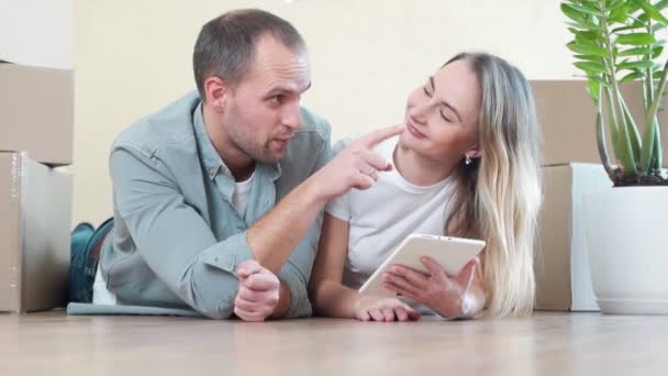 Jovem casal apaixonado se movendo em um novo apartamento, sentado no chão, planejando redecorar sua nova casa — Vídeo de Stock