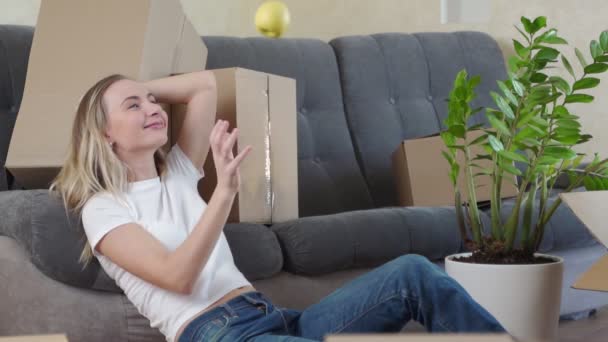 Glad ung kvinna flyttar till nytt hem - ha kul. En kvinna kastar ett äpple. — Stockvideo