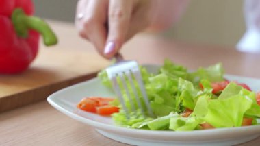 Evde sağlıklı salata yiyen bir kadın.