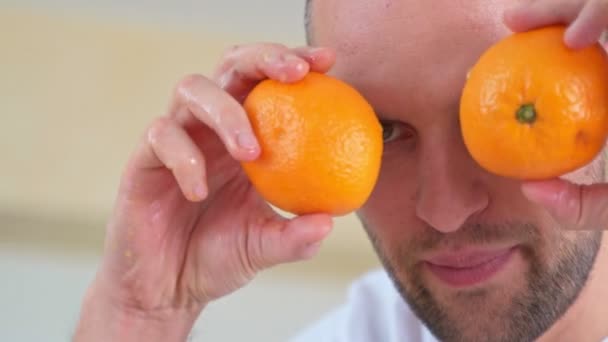 Ο άνθρωπος που κρατά δύο μισό πορτοκάλι μπροστά από τα μάτια. — Αρχείο Βίντεο