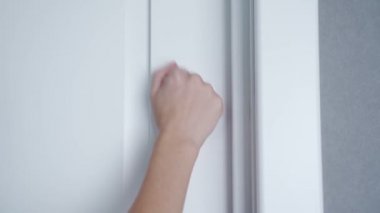 Kapı çalınıyor, eli kapalı, kapıya vuruyor.