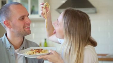 Çiftler birlikte yemek hazırlar, spagetti tadarlar.