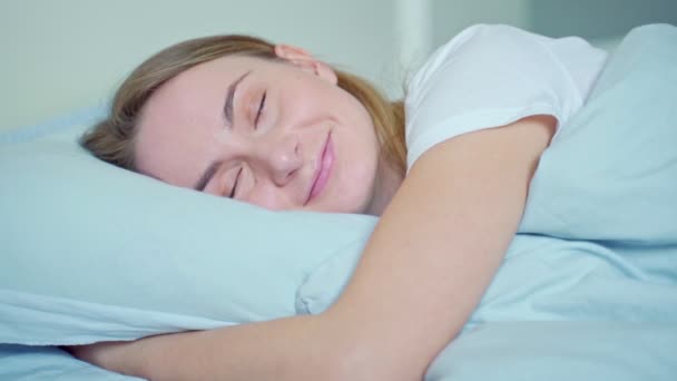 Mujer durmiendo bien en la cama abrazando suave almohada blanca. Niña adolescente descansando, buen concepto de sueño nocturno — Vídeo de stock