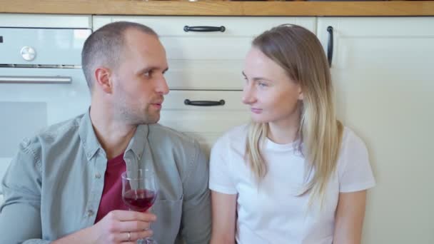 キッチンで赤ワインを飲みながらお互いを見て幸せなカップル — ストック動画