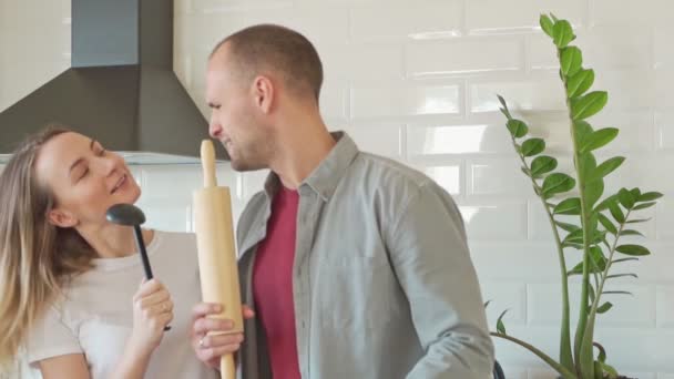 Het vrolijke echtpaar hebben plezier dansen en zingen in de keuken — Stockvideo