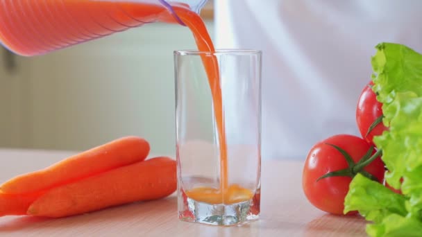 Žena ruka nalije mrkvovou šťávu do sklenice — Stock video