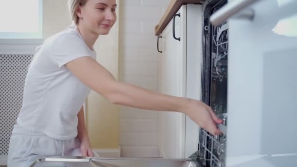 Een vrouw opent de vaatwasser in haar keuken en trekt een bril uit — Stockvideo