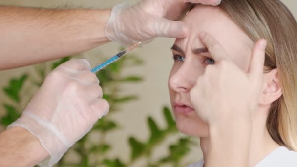 Közelkép egy szakértő kozmetikus kezéről, aki botoxot fecskendez a női homlokba. — Stock videók