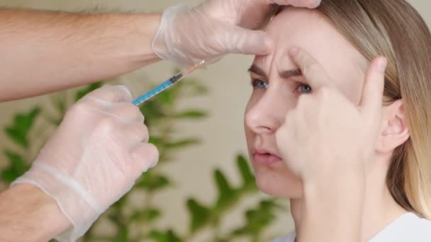 Primo piano delle mani di un estetista esperto che inietta botox nella fronte femminile — Video Stock