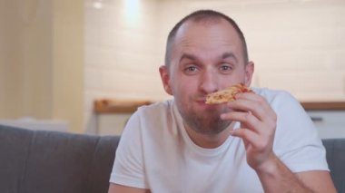 Portreci adam pizza yiyor, TV 'de en sevdiği komediyi izliyor oturma odasında kanepede dinleniyor..