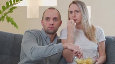 Bir çift kanepede yemek yerken korku filmi izler.