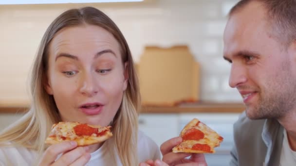 若い夫婦が居間で昼食をとっている。ピザを食べる — ストック動画