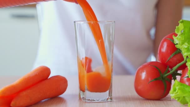 Vrouw vult glas vers wortelsap in de keuken — Stockvideo