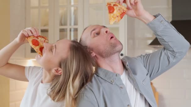 カップルは貪欲においしいピザ、ファーストフードへの中毒、不健康な食べ物を食べる. — ストック動画