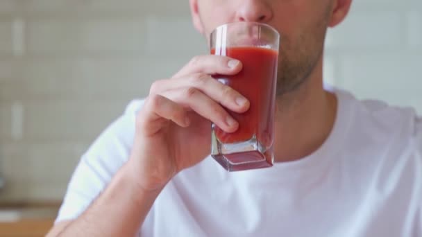 Egy férfi a konyhában paradicsomlevet iszik. — Stock videók