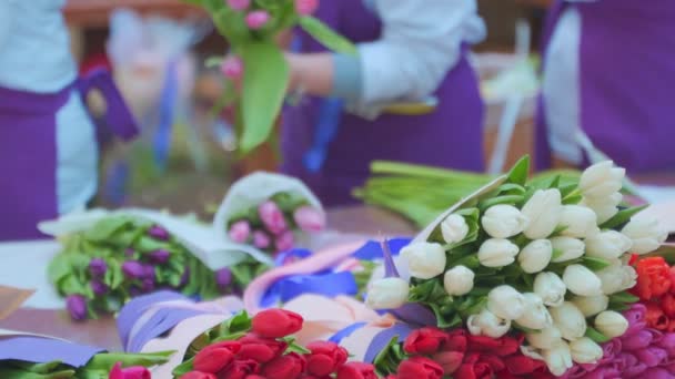 Kobieta kwiaciarnia zawijania piękny bukiet tulipanów w opakowaniu papieru rzemieślniczego — Wideo stockowe