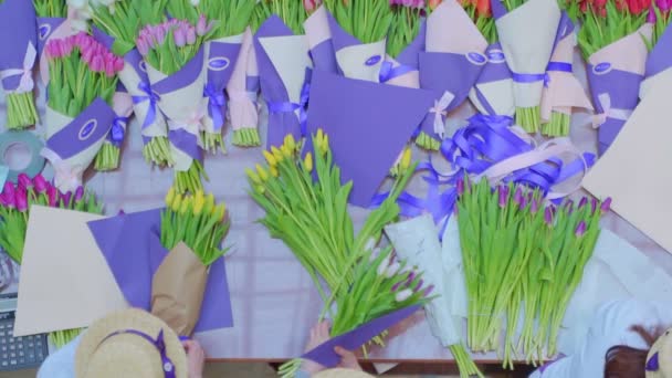 Chica florista está empacando hermosos tulipanes en una tienda de flores en papel kraft — Vídeos de Stock