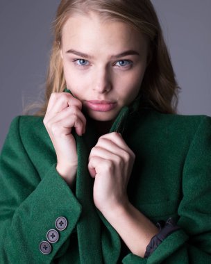 Uzun yeşil trençkotla poz veren muhteşem şık sarışın manken.