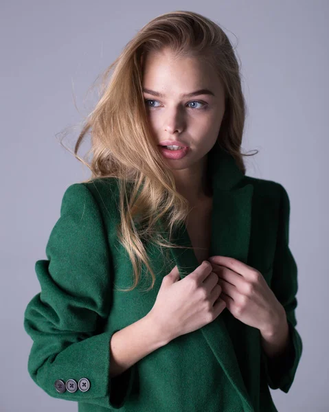 Una imagen de una atractiva y elegante rubia de pie con un abrigo verde —  Fotos de Stock