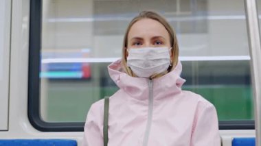 Yüzünde koruyucu maske olan bir kadın metro vagonunda oturmuş endişeli görünüyor. Salgın bölgelerin kamusal alanlarında önleyici tedbirler.
