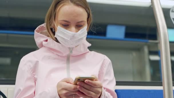 Una mujer que lleva una mascarilla quirúrgica contra un nuevo coronavirus o enfermedad coronavirus Covid-19 en un vagón subterráneo. Concepto de higiene, salud e infecciones — Vídeo de stock