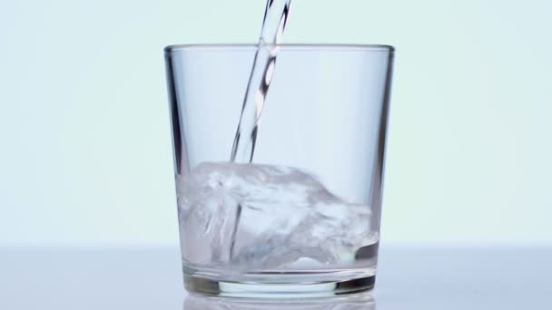 Friss tiszta víz öntése egy pohárba az asztalon, egészség és diéta koncepció. Elkülönítve, fehér háttérrel. Lassított felvétel — Stock videók