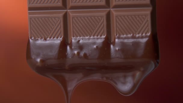 Barre de chocolat avec chocolat noir fondu dégoulinant sur un fond brun — Video