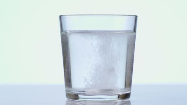 Haplar bardağa suyla düşüyor. Alevli tablet aspirin. Beyaz arkaplana yakınlaş — Stok video