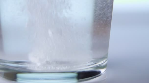 Compressa effervescente cade sul fondo del bicchiere su uno sfondo bianco . — Video Stock