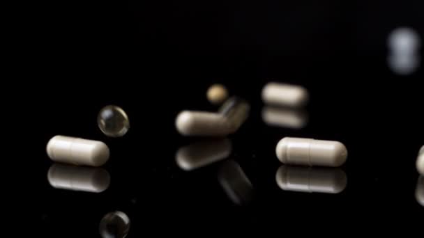 Χάπια φάρμακα κάψουλες πέφτουν κάτω και πετούν γύρω από τη λευκή επιφάνεια. Αργή κίνηση — Αρχείο Βίντεο