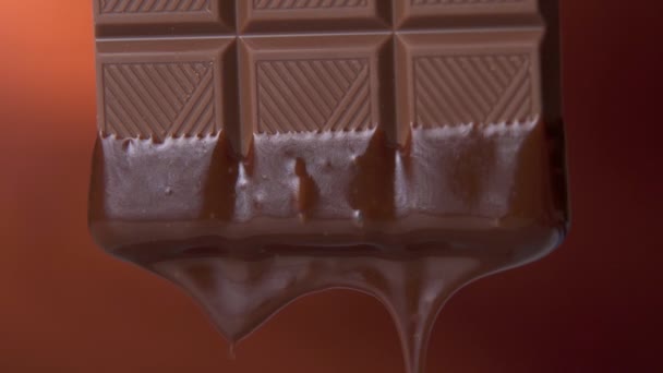 Schokoriegel mit geschmolzener dunkler Schokolade auf braunem Hintergrund