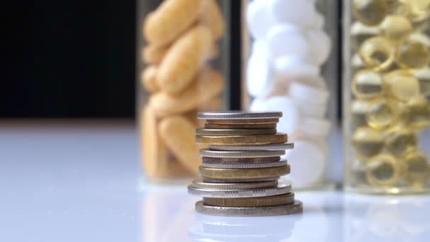 Uma pilha de moedas contra o fundo de três frascos de comprimidos — Vídeo de Stock