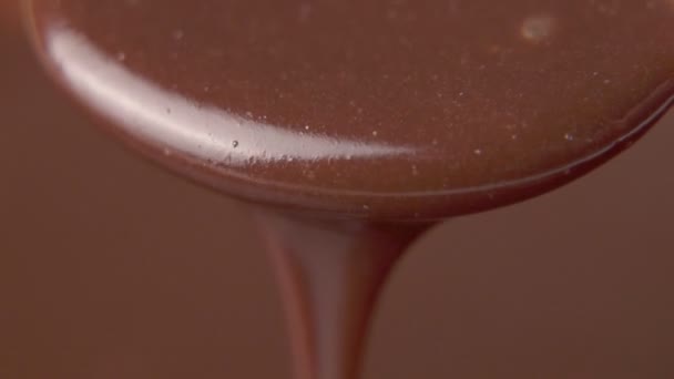 Медленное движение крупным плавлением расплавленный темный шоколад капает с ложки — стоковое видео