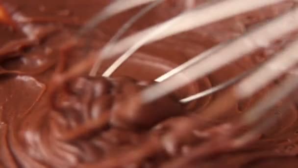 Het mengen van gesmolten vloeibare chocolade met een garde. Sluiten van vloeibare warme chocoladewerveling. — Stockvideo