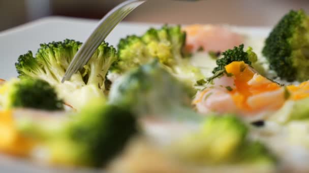 A womans hand lifts a broccoli fried egg with a fork. Close up — Stock Video