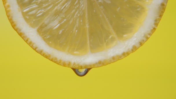 Κοντινό πλάνο ή μακροεντολή μιας φέτας λεμόνι, μια σταγόνα νερό πέφτει σε αργή κίνηση. Έννοια των φρέσκων φρούτων, κοκτέιλ. — Αρχείο Βίντεο
