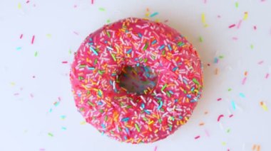 Lezzetli tatlı donut tabakta dönüyor. Üst Manzara. Parlak ve renkli donut serpiştirilmiş yakın çekim makro çekim beyaz arka planda dönüyor.