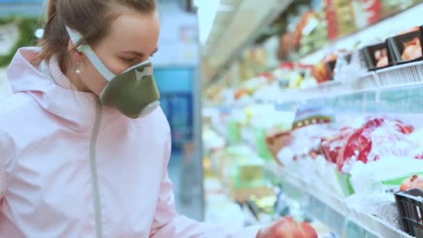 La mujer la apariencia europea en la máscara protectora respiratoria, médica en el mercado, la tienda. Escoge verduras y frutas. Coronavirus de cuarentena — Vídeo de stock